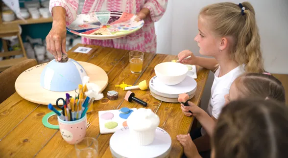 Kinder lachen beim Bemalen von Schalen